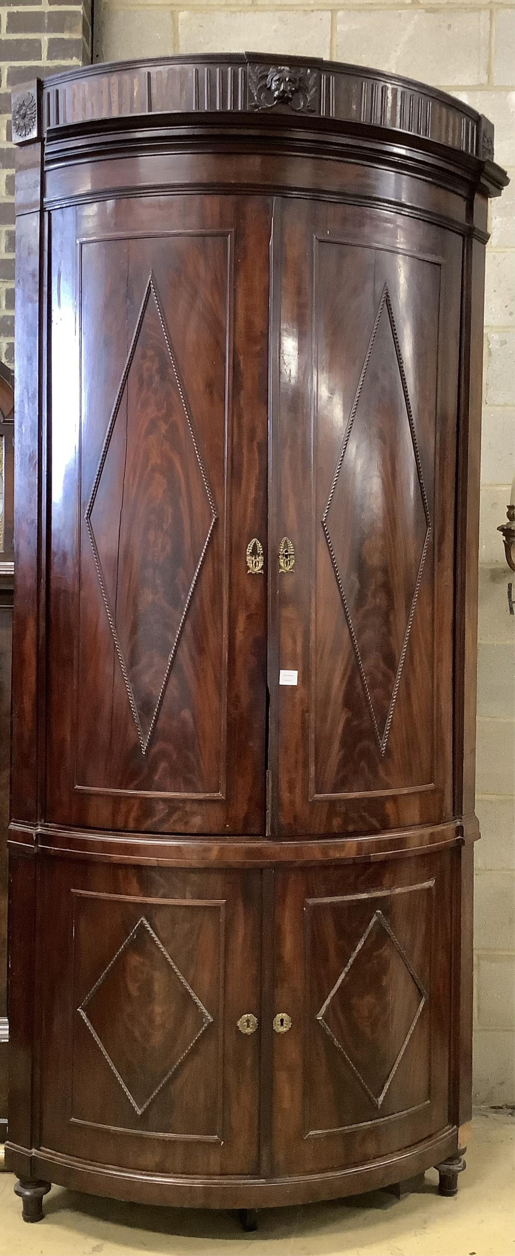 An unusually tall late 18th century Dutch mahogany bow fronted corner cabinet, in two sections, width 130cm, depth 82cm, height 265cm. Condition - fair